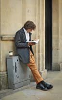 Hombre leyendo apoyado en una pared