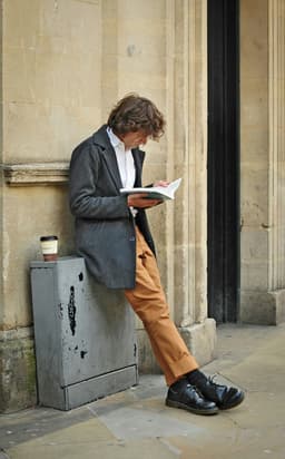 Hombre leyendo apoyado en una pared